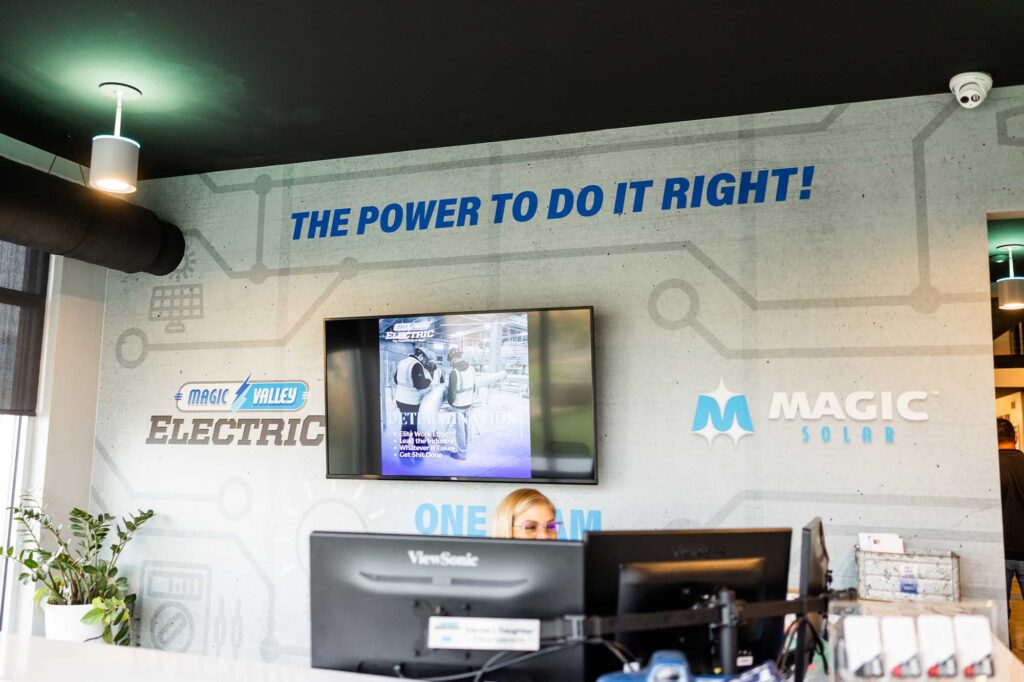 Image of an office receptionist with company logos on the wall behind her